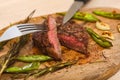 Juicy medium Beef Rib Eye steak slices on wooden board with fork and knife