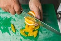 A juicy orange being sliced into segments on a gree fruit only cutting board