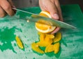 A juicy orange being sliced into segments on a green fruit and vegetable chopping board. organic fruit and vegetables