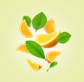 Juicy orange slices and green leaves flying on cream background Royalty Free Stock Photo