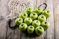 Juicy organic green apples and cotton string mesh bag on a wooden table