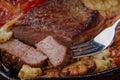 Juicy piece of steak on a fork with fried vegetables close-up. Royalty Free Stock Photo