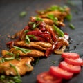 Juicy pieces of fried meat with vegetables on a black plate. Food background. Close up shot. Appetizer dish from