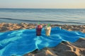 Pieces of fruit in glasses on a blue blanket on the sandy beach. watermelon and melon at sunset. background for the design. Royalty Free Stock Photo