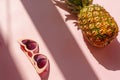 Juicy pineapple and pink sunglasses on trendy pink paper backgro