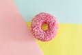 Juicy Pink Sprinkled Donut on a Geometric Pink, Blue and Yellow Background