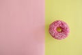 Juicy Pink Sprinkled Donut isolated on a Pink and Yellow Background
