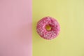 Juicy Pink Sprinkled Donut isolated on a Pink and Yellow Background