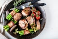 Juicy pork medallions wrapped in bacon, serve on the iron pan on the dark wooden dackground. Close up. Royalty Free Stock Photo
