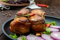 Juicy pork medallions wrapped in bacon, serve on the iron pan on the dark wooden dackground. Royalty Free Stock Photo