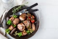 Juicy pork medallions wrapped in bacon, serve on the iron pan on the dark wooden dackground. Close up. Royalty Free Stock Photo