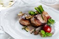 Juicy pork medallions wrapped in bacon, serve on the iron pan on the dark wooden dackground. Close up. Royalty Free Stock Photo