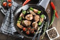 Juicy pork medallions wrapped in bacon, serve on the iron pan on the dark wooden dackground. Close up. Royalty Free Stock Photo