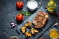 Juicy pork steak with spices and grilled mushroomson dark stone background