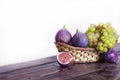 Juicy raisins and several ripe figs in a fruit basket on a white and dark wooden background. fresh fruits, natural vitamin