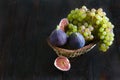 Juicy raisins and several ripe figs in a fruit basket on a white and dark wooden background. fresh fruits, natural vitamin