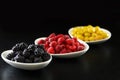 Raspberry, blackberries and dogeberry in white plate on black background Royalty Free Stock Photo