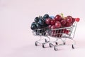 Juicy red and black grapes in grocery baskets on a light background.