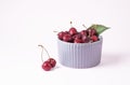 Juicy red cherries in a gray bowl on a pink background. Front view and copy space