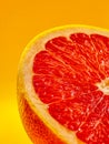 Juicy red grapefruit half against a vibrant yellow background Royalty Free Stock Photo