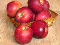 Juicy red organic apples in a basket on oak tree wood background. Autumn Fall season orchard harvest production. Royalty Free Stock Photo