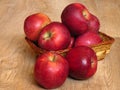 Juicy red organic apples in a basket on oak tree wood background. Autumn Fall season orchard harvest production. Royalty Free Stock Photo