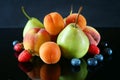 Juicy red ripe pears, plums, apricot, strawberries, blueberries, peach fruits on black background Royalty Free Stock Photo
