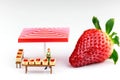 Juicy red strawberry on white background with miniature farmer