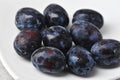 Juicy ripe black and blue plums on a plate Royalty Free Stock Photo