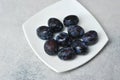 Juicy ripe black and blue plums on a plate Royalty Free Stock Photo