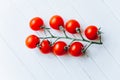 Juicy ripe cherry tomatoes on a green twig on a white wooden background Royalty Free Stock Photo