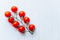 Juicy ripe cherry tomatoes on a green twig on a white wooden background Royalty Free Stock Photo