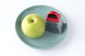 Juicy ripe green apple and a small grater on a turquoise plate, isolated on a white background Royalty Free Stock Photo