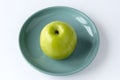 Juicy ripe green apple on a turquoise plate, isolated on a white background Royalty Free Stock Photo