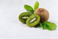 Juicy ripe green kiwi with wet slice section, young leaf on white wood background, closeup, border.