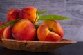 Juicy and ripe peaches lie in a carved wooden plate Royalty Free Stock Photo