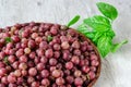 Juicy ripe red berries of a gooseberry in a small wicker round basket and a sprig of fresh basil on a wooden background Royalty Free Stock Photo