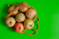 Juicy ripe red-yellow apples lie in a knitted bag on a green background Royalty Free Stock Photo