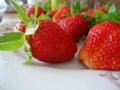 Juicy ripe strawberries with leaves on a plate, mouthwatering berry