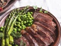 Juicy roasted beef chopped steak, with green peas, asparagus, on plate close up Royalty Free Stock Photo