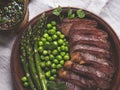 Juicy roasted beef sliced steak, with green peas, roasted asparagus, on plate Royalty Free Stock Photo