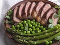 Juicy roasted beef sliced steak, with green peas, roasted asparagus, on plate Royalty Free Stock Photo