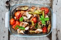 Juicy sausages and grilled vegetables in a glass bowl on a nature background