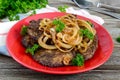 Juicy slices of fried liver and onions on a red plate