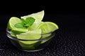 Juicy slices of lime and mint on a black background in drops of water. Royalty Free Stock Photo