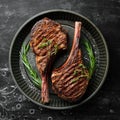 Juicy steak grilled on the bone with spices and herbs. On a black stone background. Top view. Free copy space Royalty Free Stock Photo