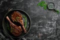 Juicy steak grilled on the bone with spices and herbs. On a black stone background. Top view. Free copy space Royalty Free Stock Photo