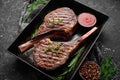 Juicy steak grilled on the bone with spices and herbs. On a black stone background. Top view. Free copy space Royalty Free Stock Photo