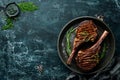 Juicy steak grilled on the bone with spices and herbs. On a black stone background. Top view. Free copy space Royalty Free Stock Photo