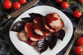 Juicy steak well done roast pork with red sauce and Basil leaves on a white plate over a black marble table Royalty Free Stock Photo